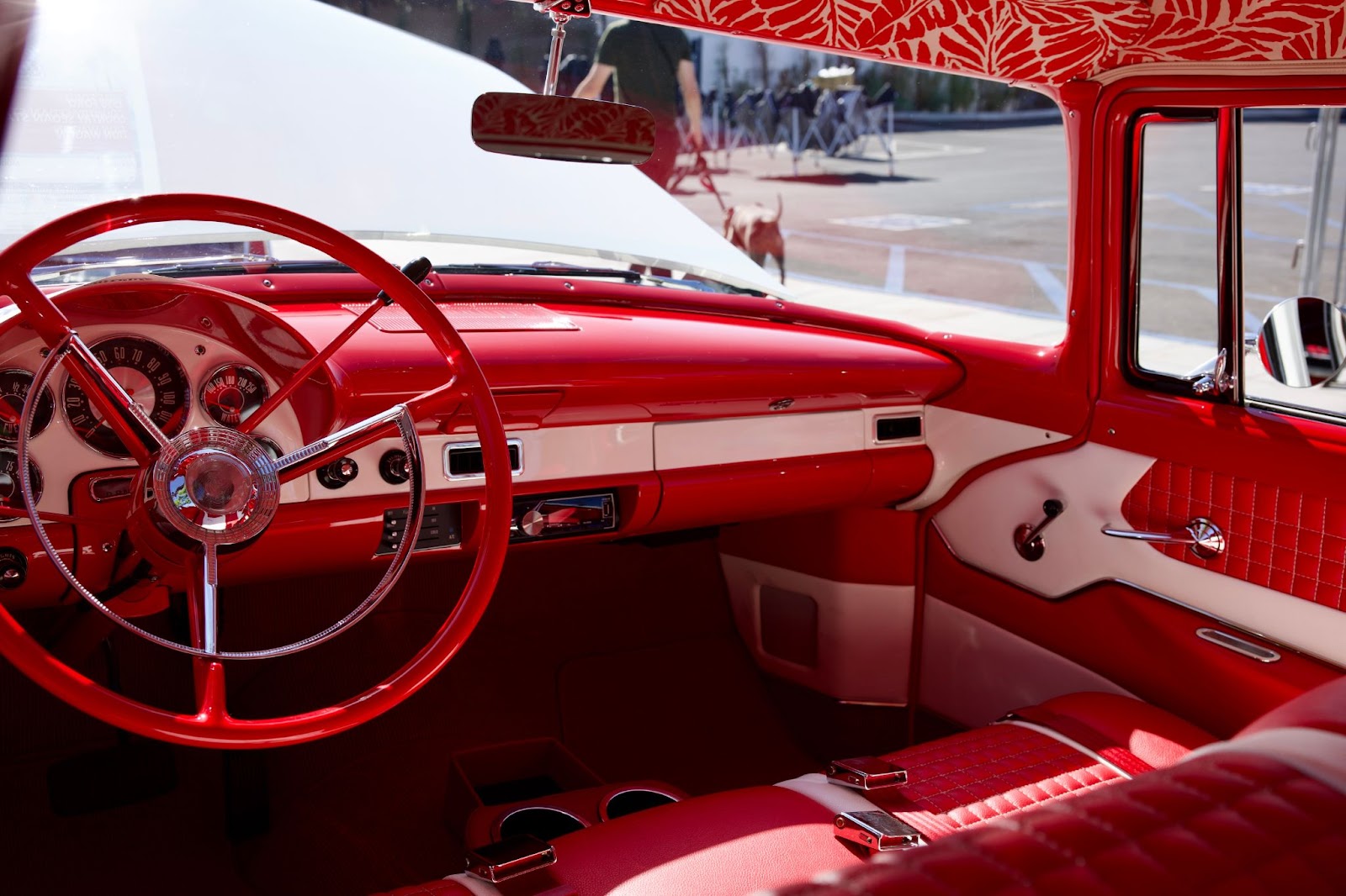 Vintage red car interior with white accents and a classic steering wheel.