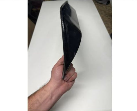 Black rectangular object held by a hand on a white surface.