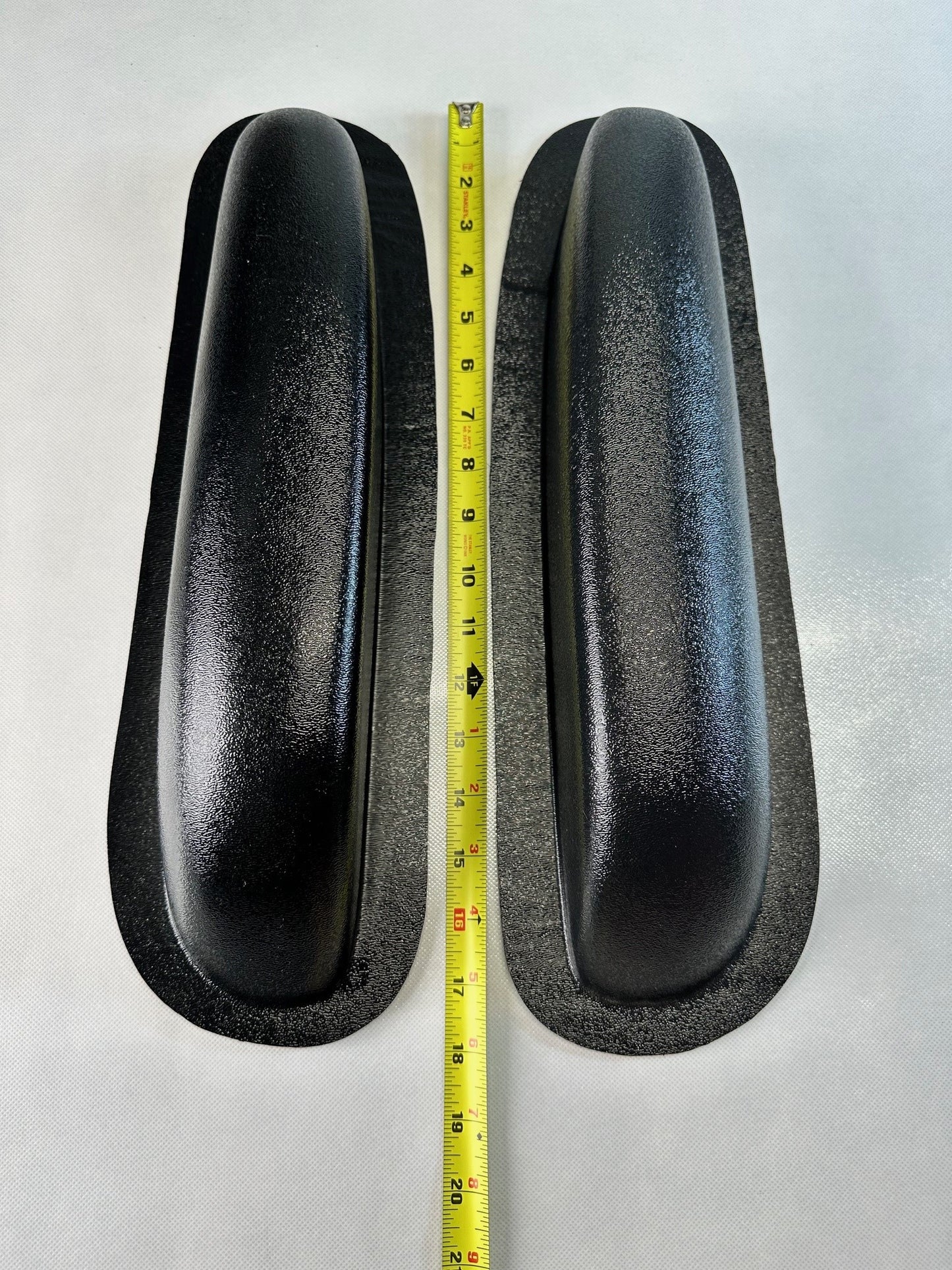 Two black rubber pads with a measuring tape between them on a white background