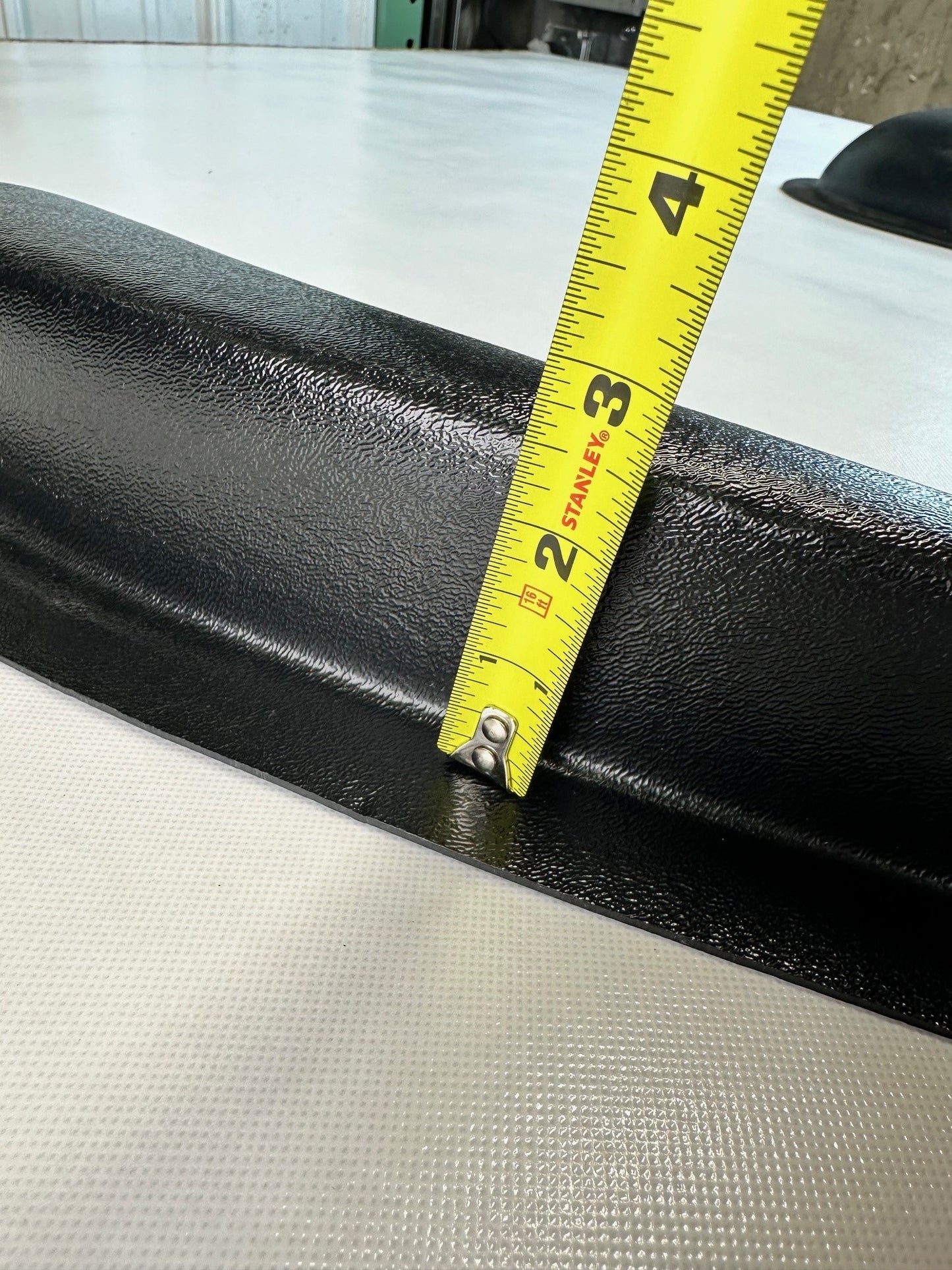 Black leather seat with a measuring tape indicating dimensions on a white surface.