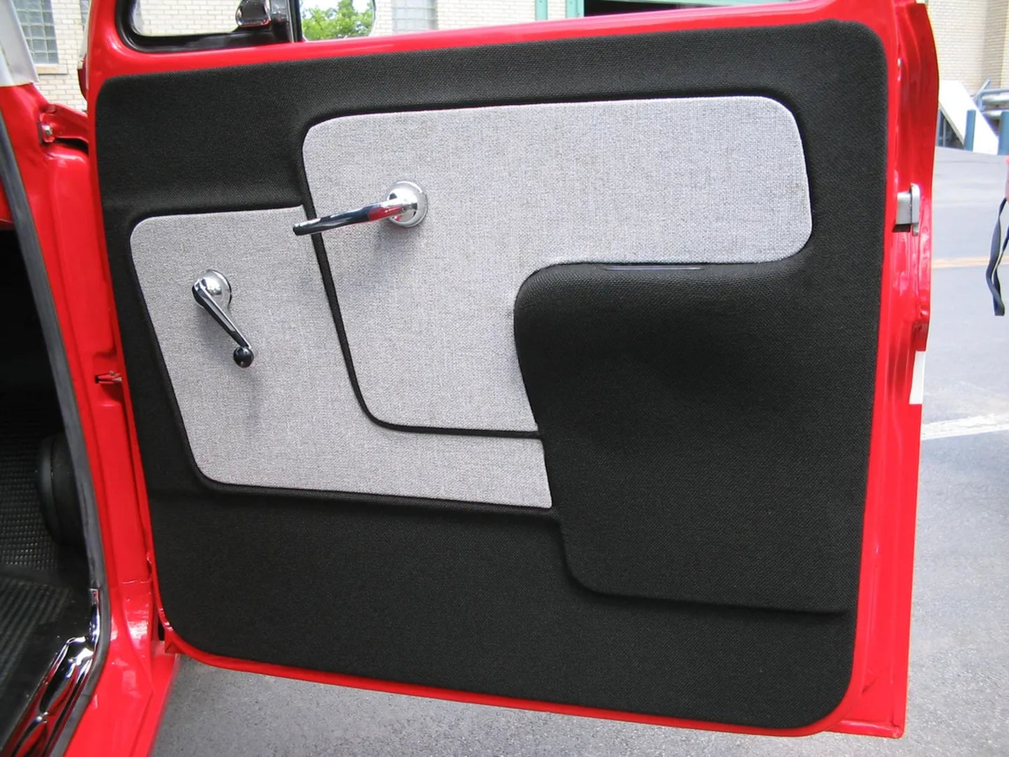 A photo showing a red Chevrolet truck door panel with a black and gray armrest area.