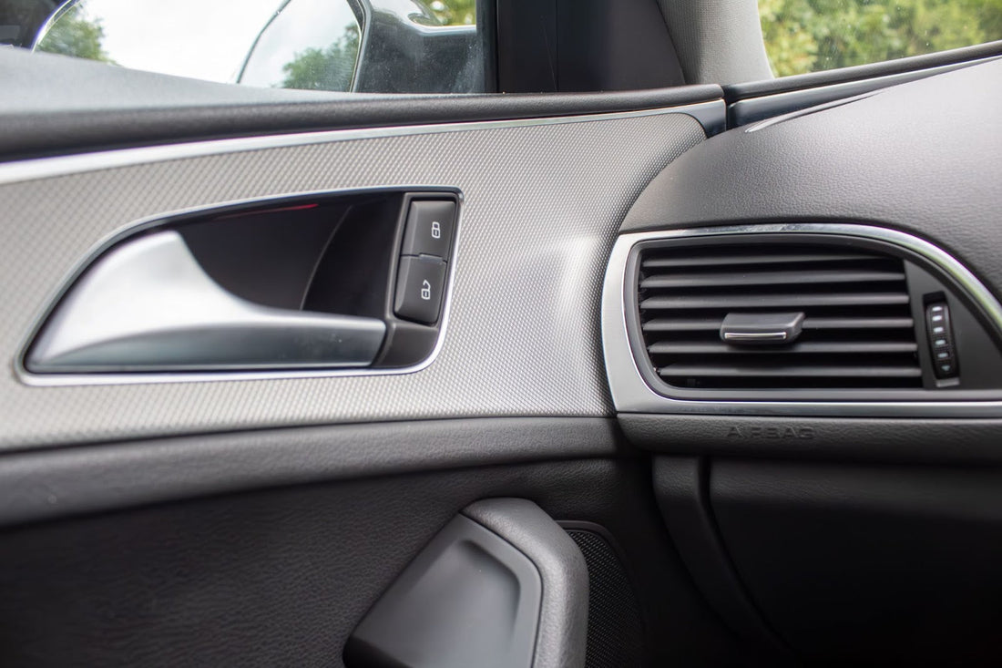 Interior of a car door with window controls and air vent.