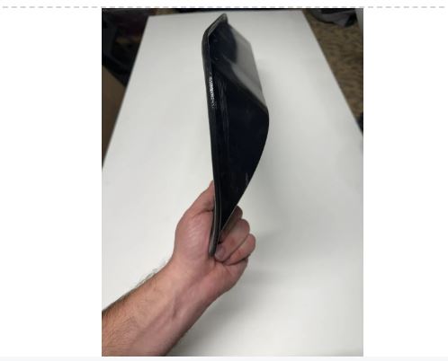 Black rectangular object held by a hand on a white surface.