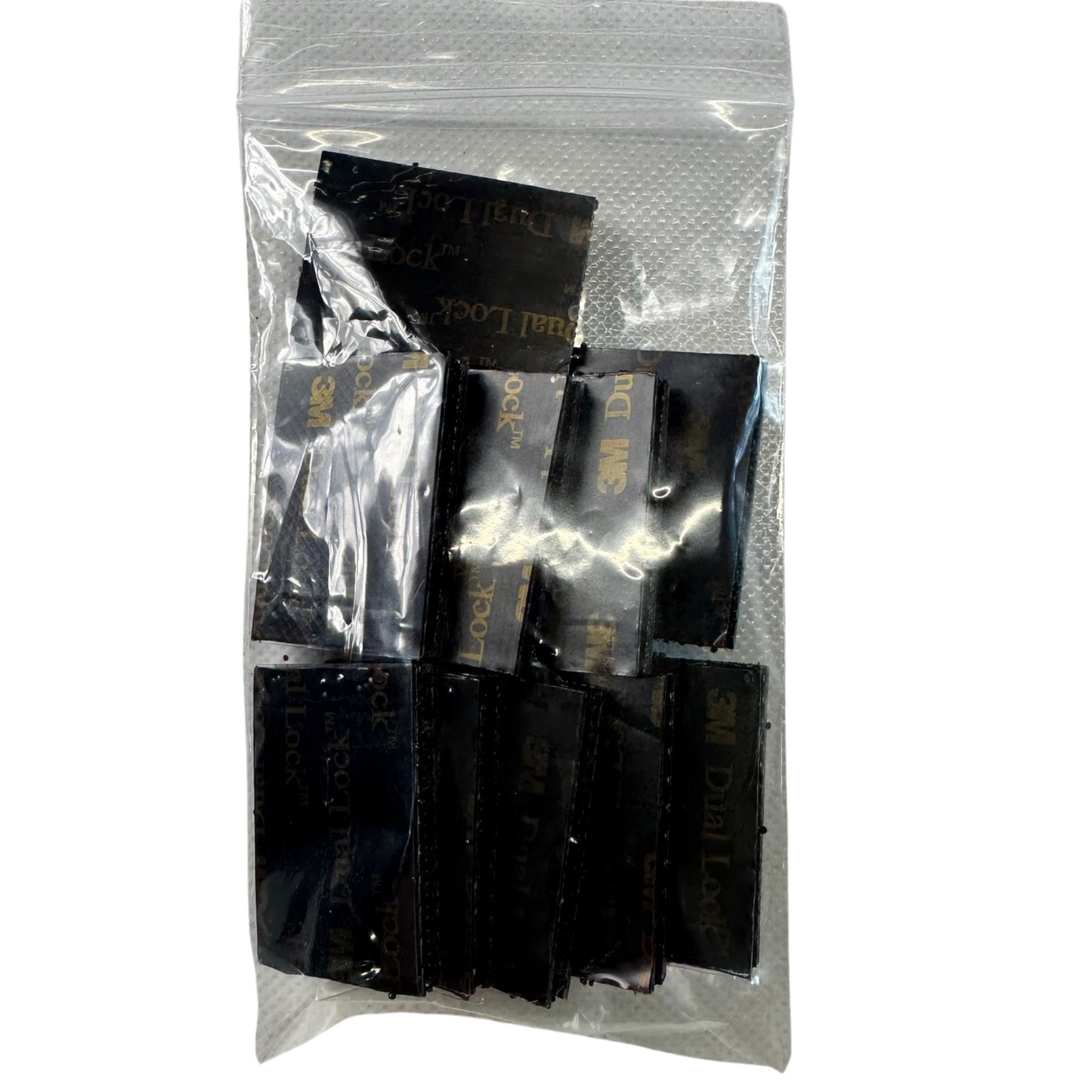 Packaged black dual lock tabs with visible branding on a white background