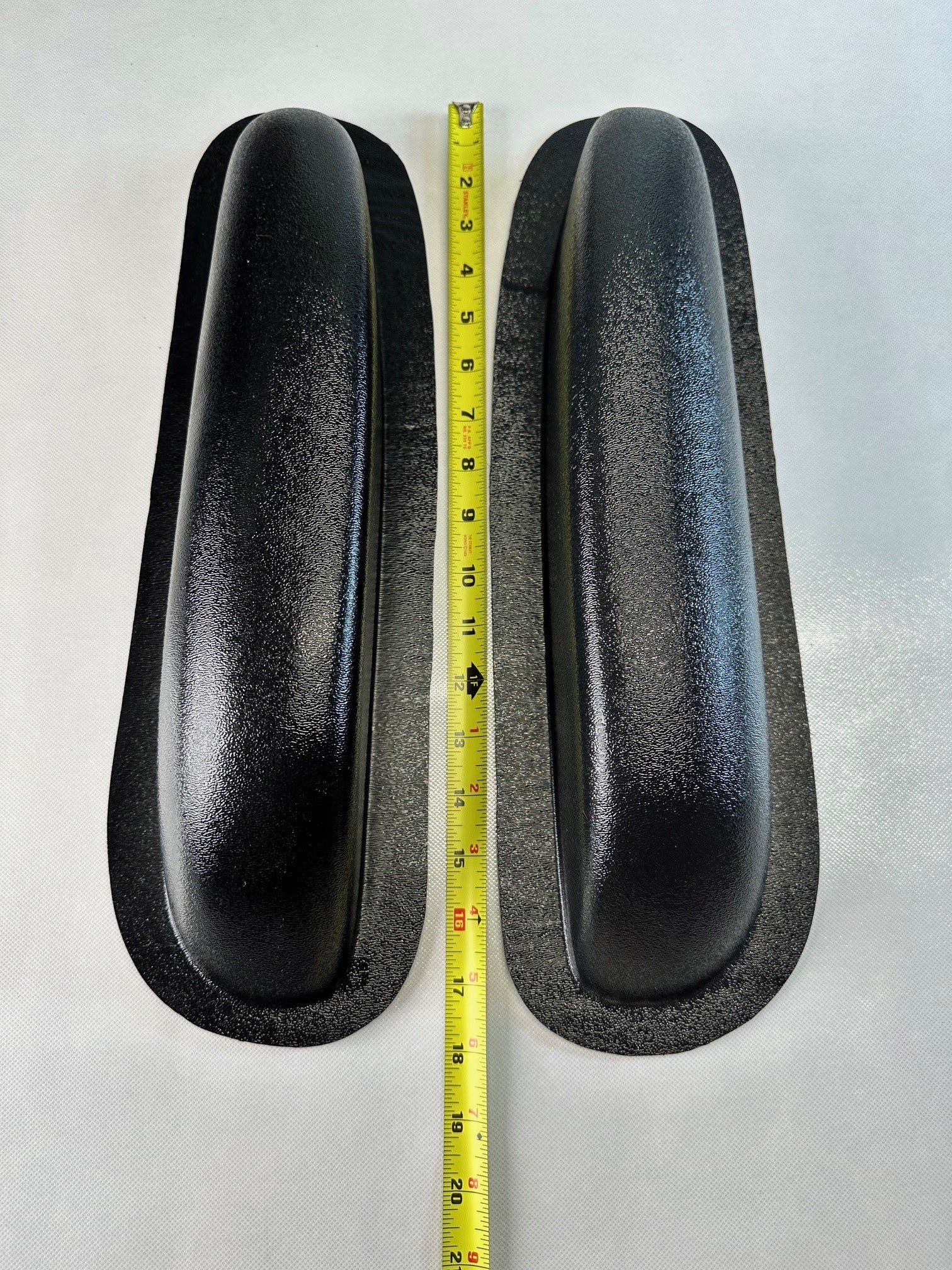 Two black rubber pads with a measuring tape between them on a white background