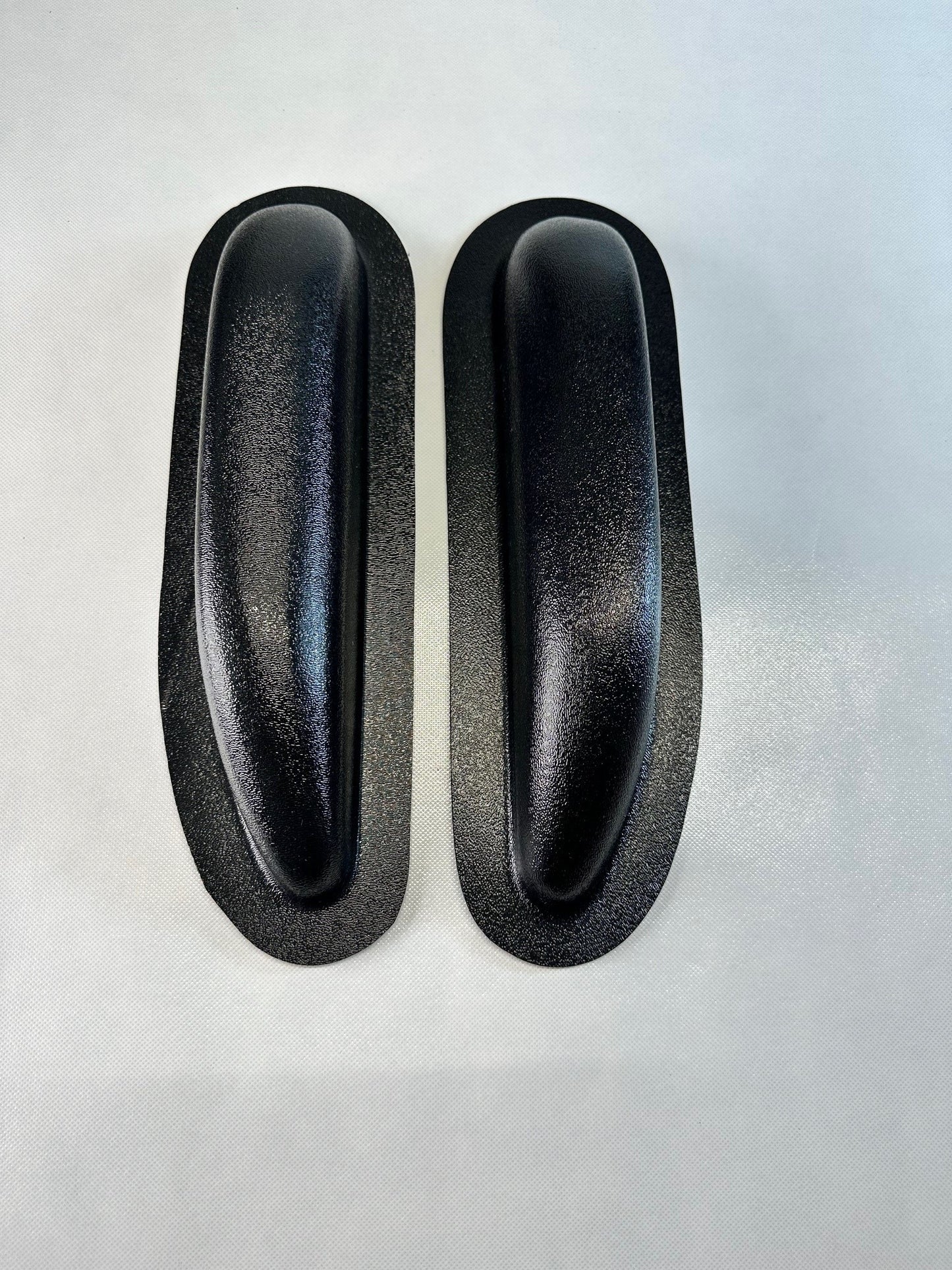 Pair of unfinished black ABS universal modular armrests, driver and passenger side shown side by side