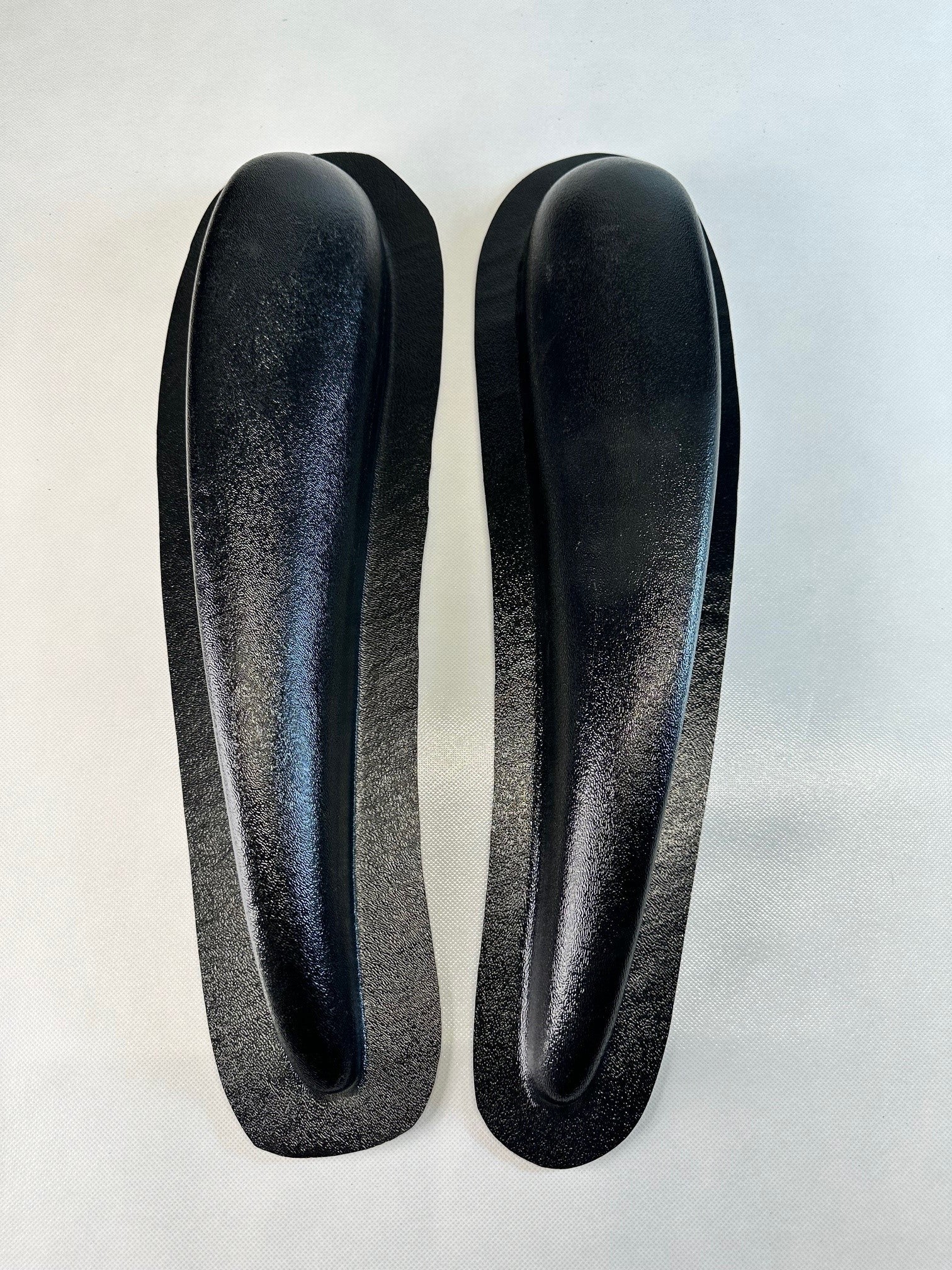 Two black shoe inserts on a light gray background