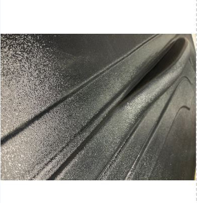 Textured black surface, plastic. Showing the armrest is raised off of the door panel