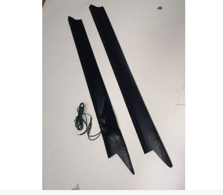Two black car side skirts with a wiring harness on a white background