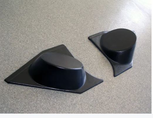 A pair of black kick panels with integrated speaker pods for 1973-1987 Chevrolet trucks, displayed on a grey surface.