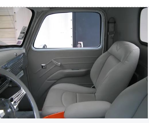 Gray interior of a vehicle with steering wheel and seats.