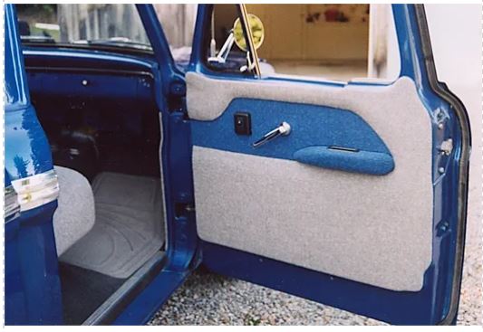 A blue and white door panel with armrest for a 1961-1966 Ford truck, with the door partially open, installed on a blue vehicle.