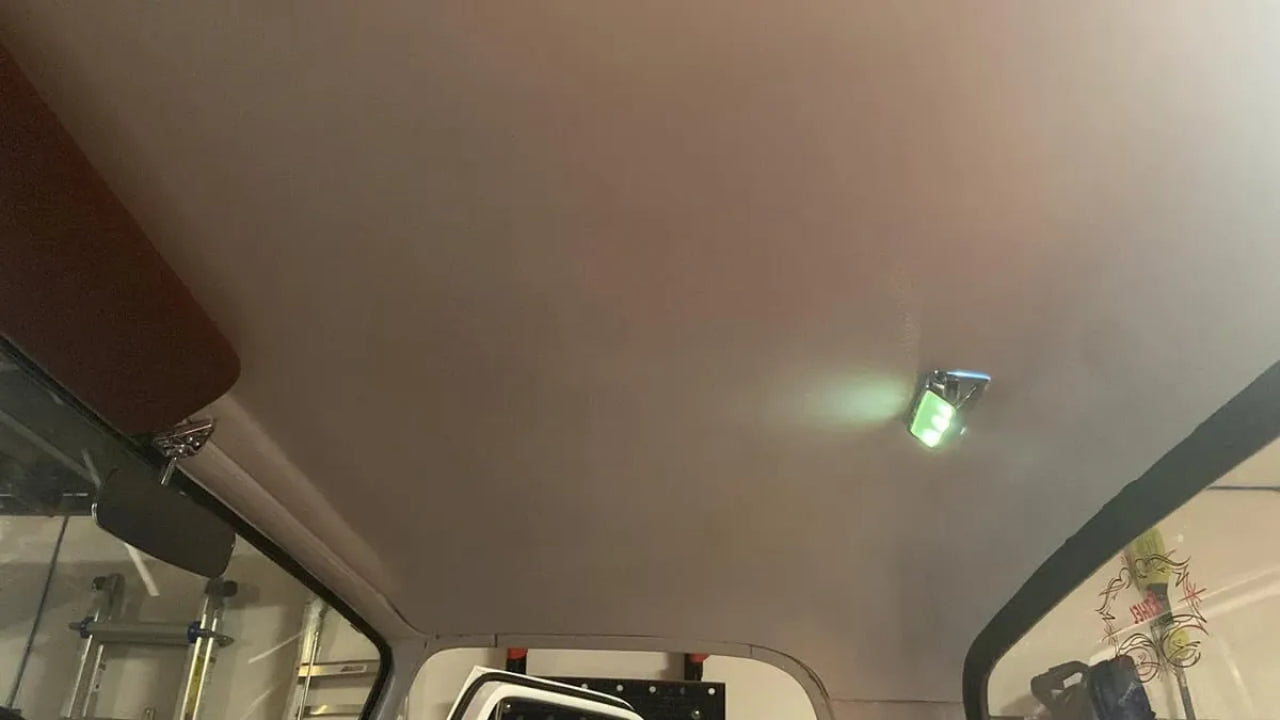 An image showing the interior roof of a vehicle, specifically the headliner, which appears to be white and is pretrimmed for a big window model.