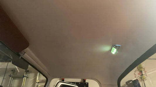 An image showing the interior roof of a vehicle, specifically the headliner, which appears to be white and is pretrimmed for a big window model.