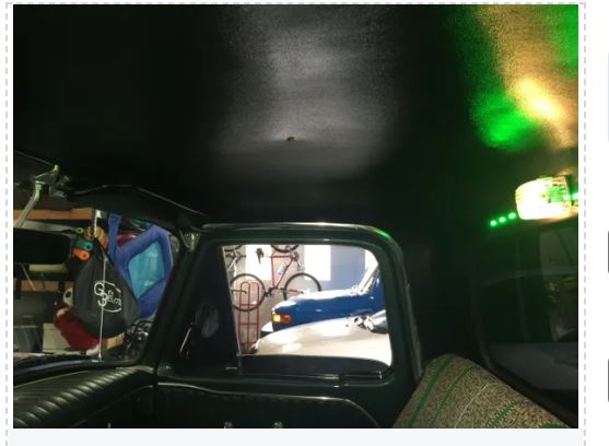 View from inside a vehicle looking out through a rearview mirror into a dark garage.
