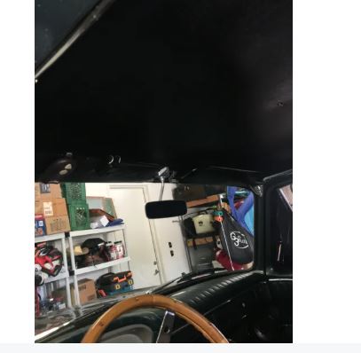 Vintage car interior with wooden steering wheel in a garage setting