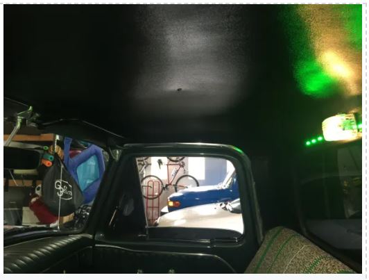 View from inside a vehicle looking out to a garage with various items and a bicycle.