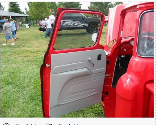 Red car door open with people and tents in the background