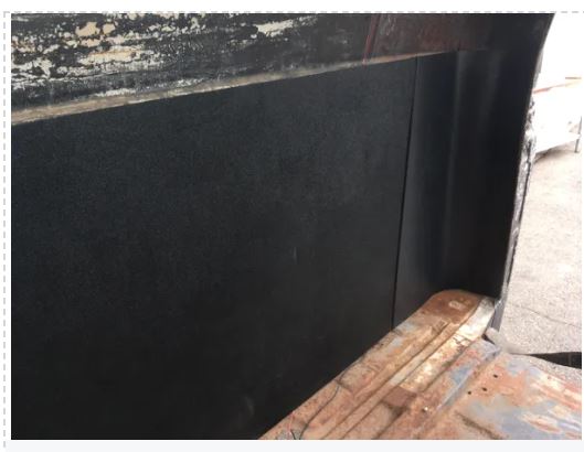 Close-up of a black metal surface with a textured finish, possibly part of a vehicle or machinery.