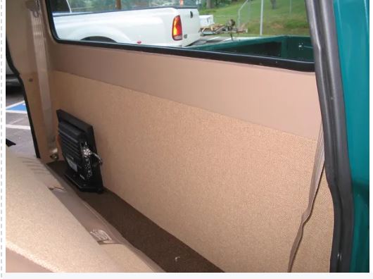 Rear cab cover installed on the interior rear side of a vehicle, appears to be beige or tan in color and smooth in texture.