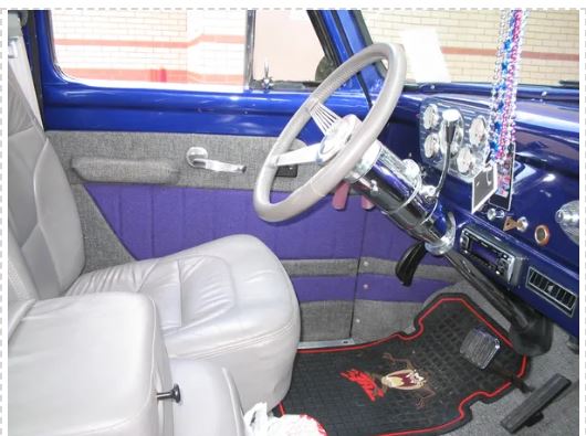 Interior of a classic vehicle with a steering wheel and dashboard.