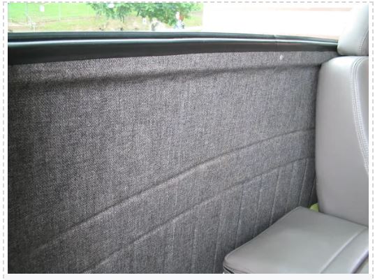 Car interior with gray textured partition and white seat