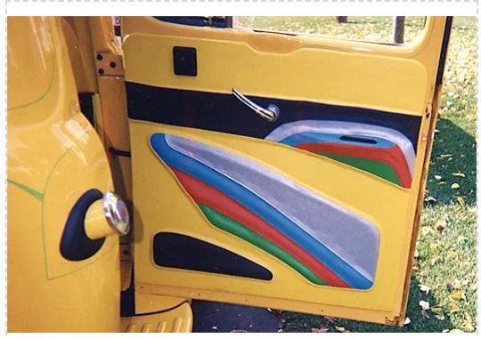 Yellow vehicle door with colorful cutout shapes on a grassy background