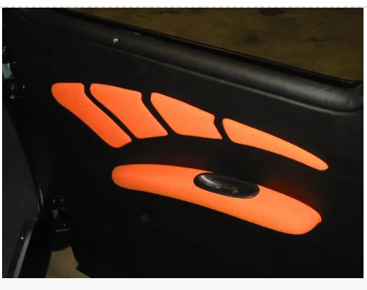 Close-up of a black vehicle door with orange graphics on a dark background