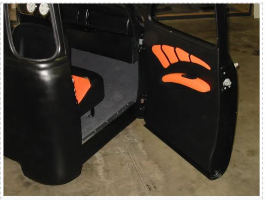 Black vehicle door with orange graphics on a concrete floor.