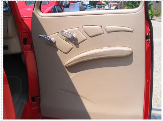 Beige car door panel with window controls and handle, red car exterior visible