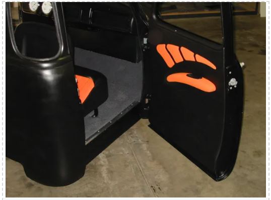 Black golf cart door with orange paw prints on a concrete floor.