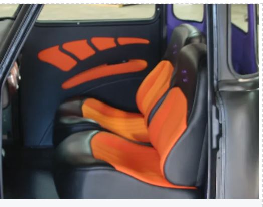Car interior with orange and black seat covers on a gray car seat.