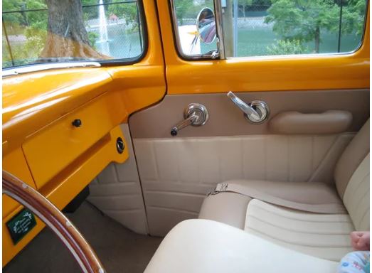Interior of a vintage vehicle with yellow exterior and beige interior.