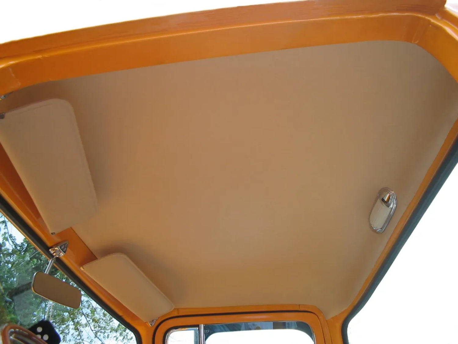 A beige-colored ABS rubberless headliner panel by Rod Doors installed inside the cab of a vintage Ford truck