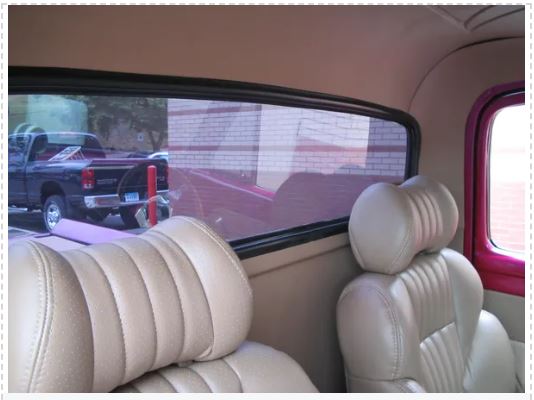 Beige interior of a vehicle with headrests and a view of an outdoor scene through the window.
