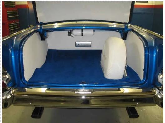 Blue car trunk with white interior and spare tire.
