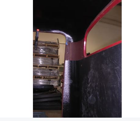 Rear cab cover for a Studebaker truck, showing the cover fitted on the vehicle's rear windshield area, with storage shelves in the background.
