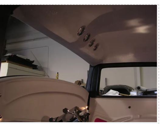 Interior view of a vehicle with a brown ceiling and various components.