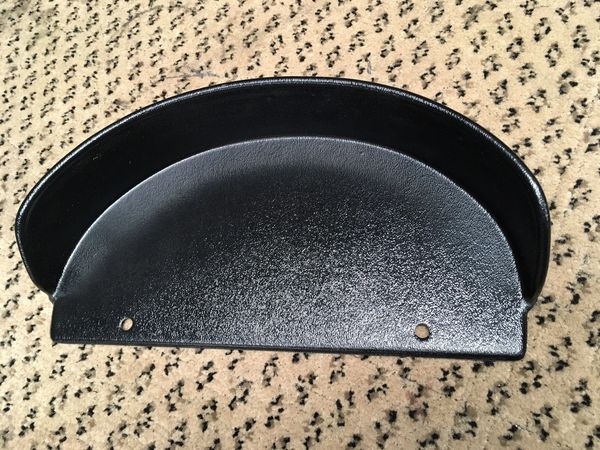 A black, semi-circular dash panel for a Ford truck, placed on a patterned surface.